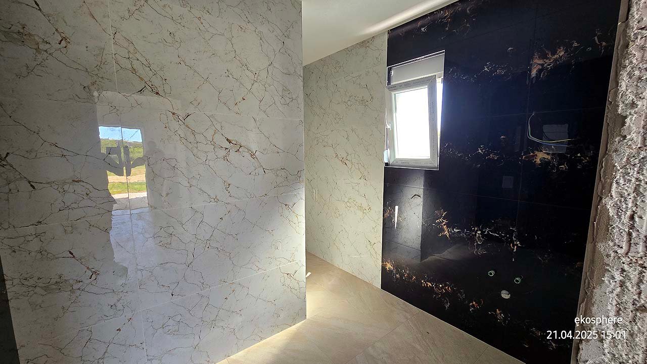 Modern bathroom in Ulcinj features marble tiles, black accent wall, natural light. Top Montenegro real estate by Ekosphere, on immorenta.me.