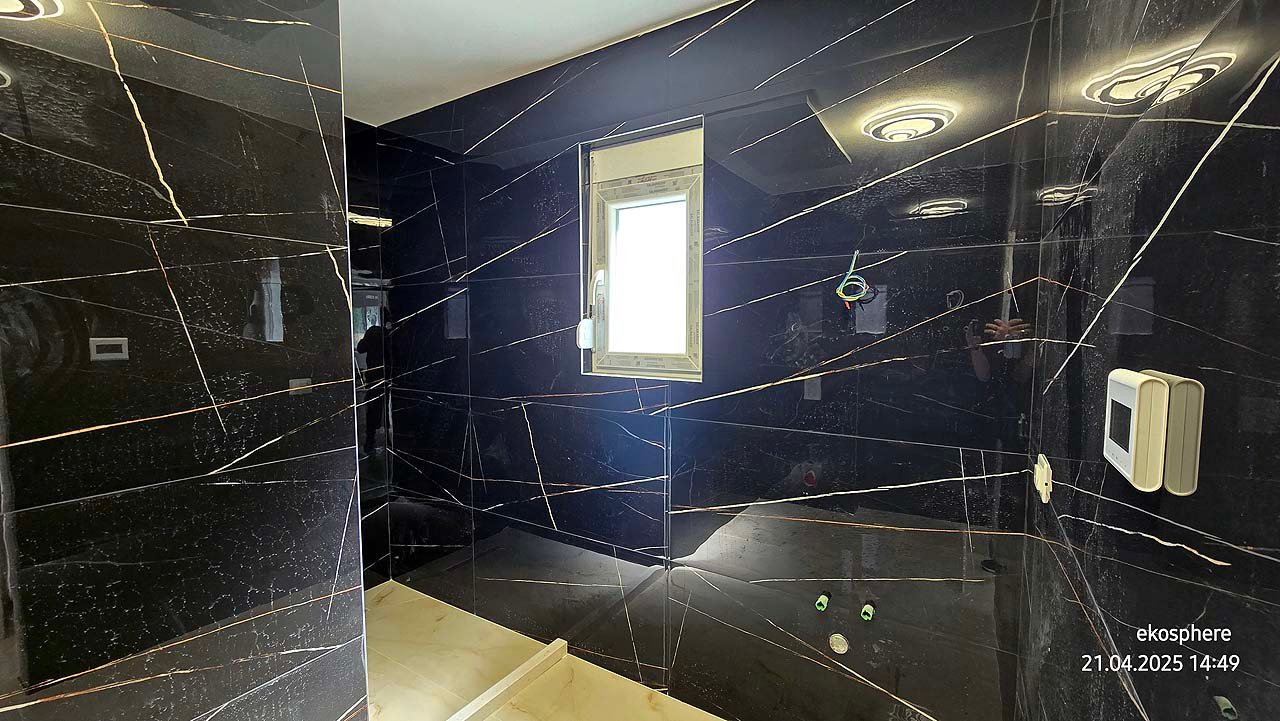 Modern Ulcinj bathroom with black marble walls, white fixtures, and natural light&mdash;exclusive at immorenta.me by Ekosphere.