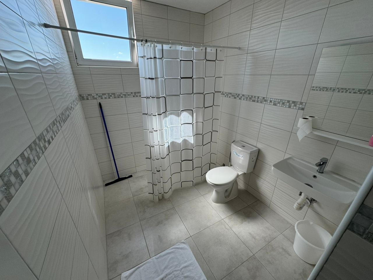 Modern tiled bathroom in Ulcinj property: shower, window, sink. Great investment on immorenta.me by ekosphere doo.