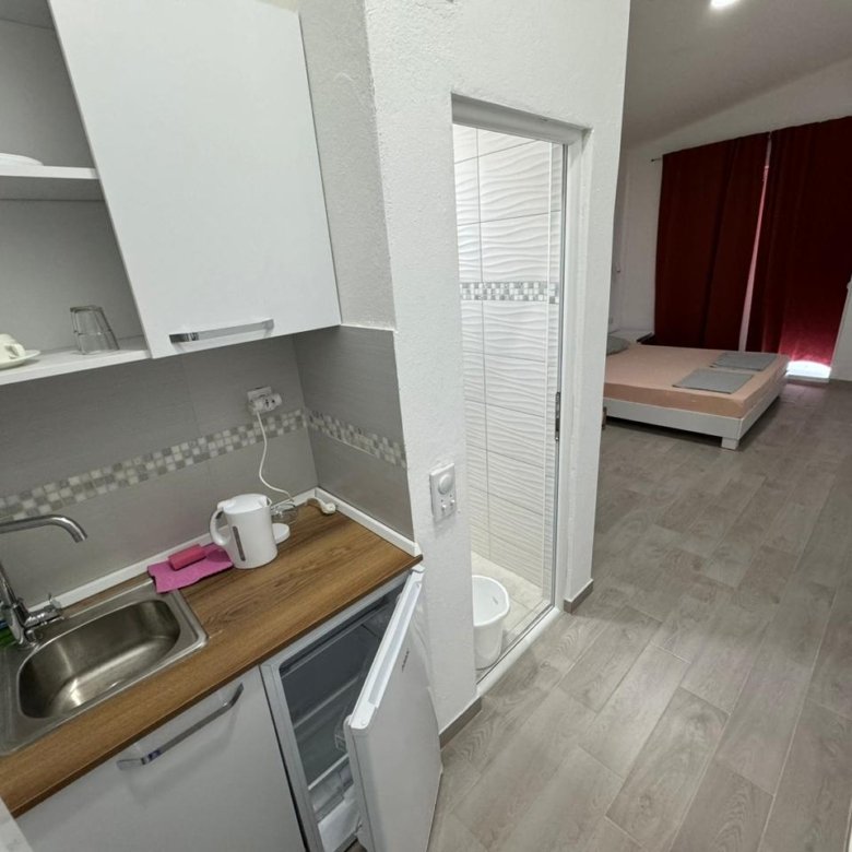 Modern studio apartment in Ulcinj with kitchenette, bed, red curtains; prime investment from Ekosphere via immorenta.me.
