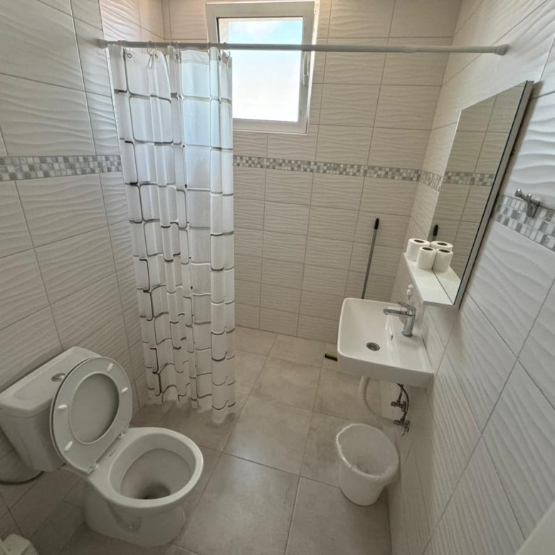 Modern tiled bathroom in Ulcinj Montenegro property: shower, wall sink, window. Smart real estate investment via immorenta.me by ekosphere doo.