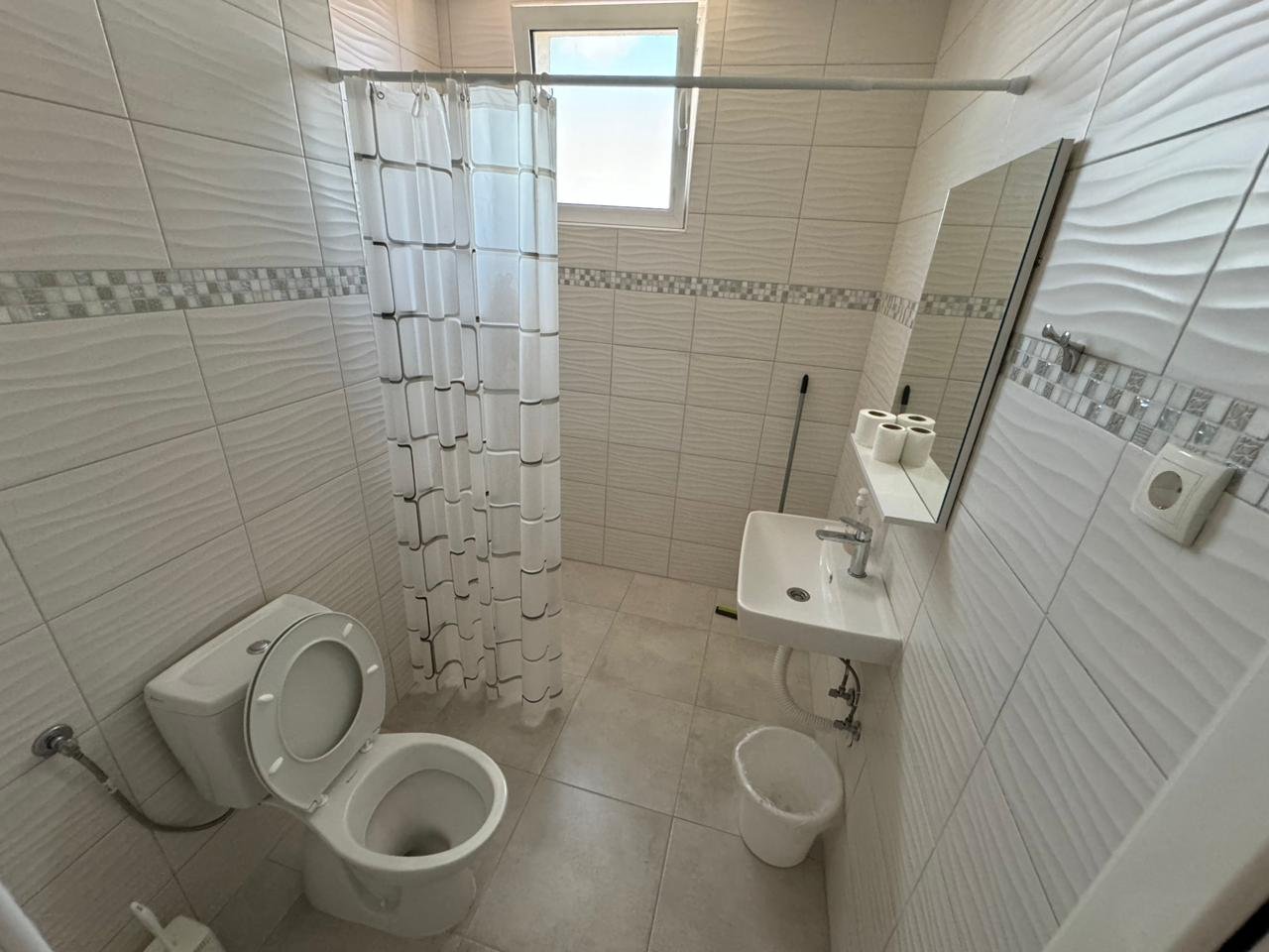 Modern tiled bathroom in Ulcinj Montenegro property: shower, wall sink, window. Smart real estate investment via immorenta.me by ekosphere doo.