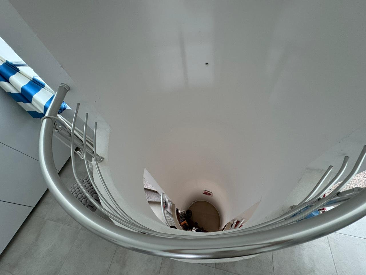 Elegant spiral staircase with metal railings and white walls, ideal Ulcinj property; ekosphere window highlights investment appeal.