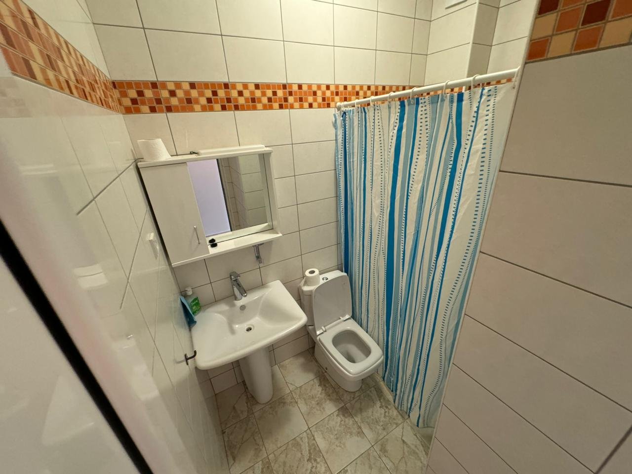 Modern small bathroom in Ulcinj with white tiles, pedestal sink, shower, ideal for property investment from Montenegro-Listings.me/Ekosphere doo.