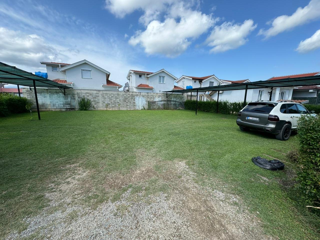 Prime Ulcinj real estate: modern homes with white walls, red roofs, carports, and green parking. Exclusive on immorenta.me by ekosphere doo.