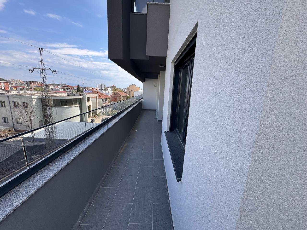 Modern balcony with glass railing and gray tiles, prime Ulcinj real estate; great views&mdash;exclusive on immorenta.me by ekosphere doo.