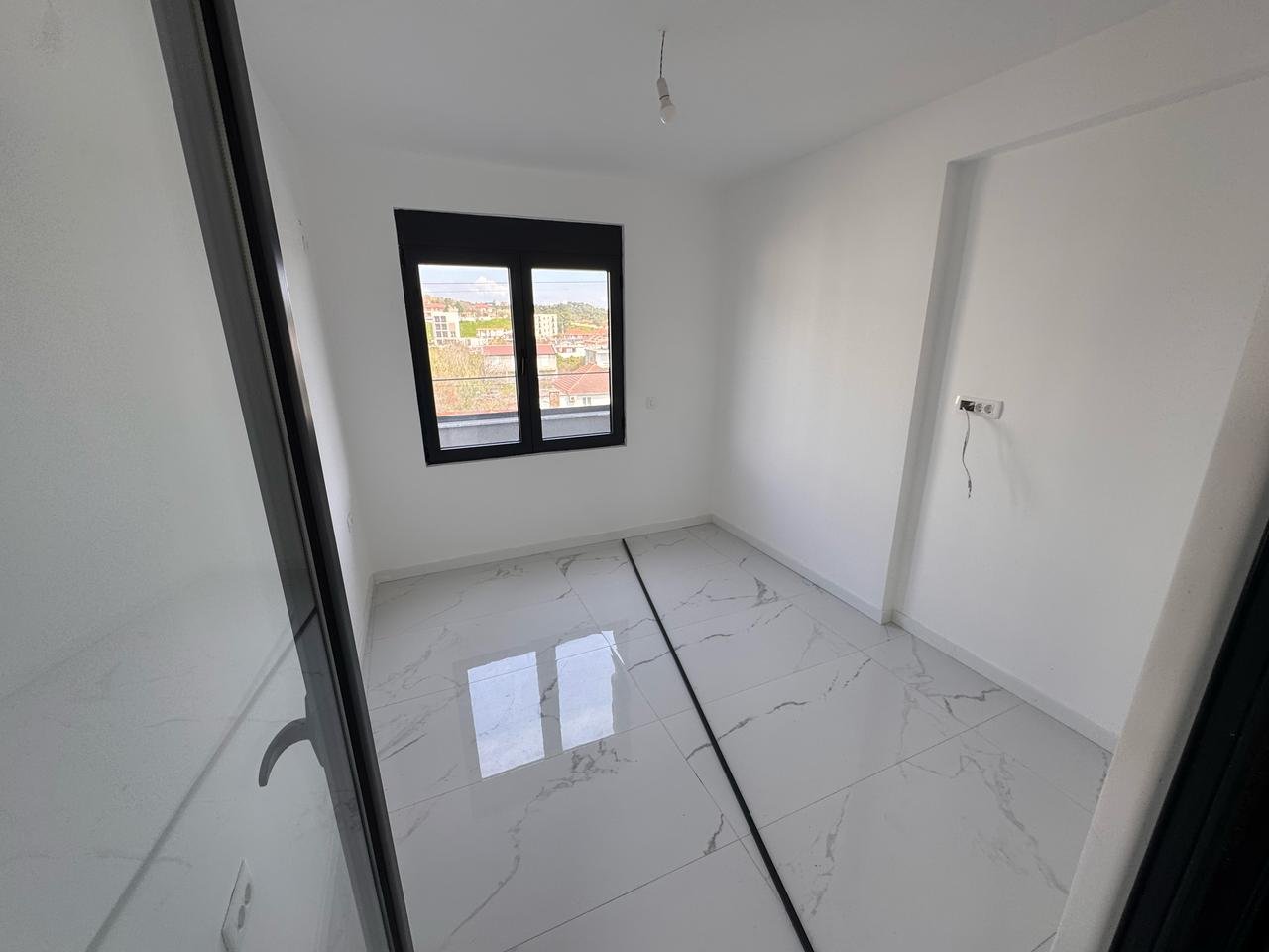 Modern, light-filled Ulcinj property: pristine white walls, glossy tiled floors, large window&mdash;prime investment via ekosphere doo.