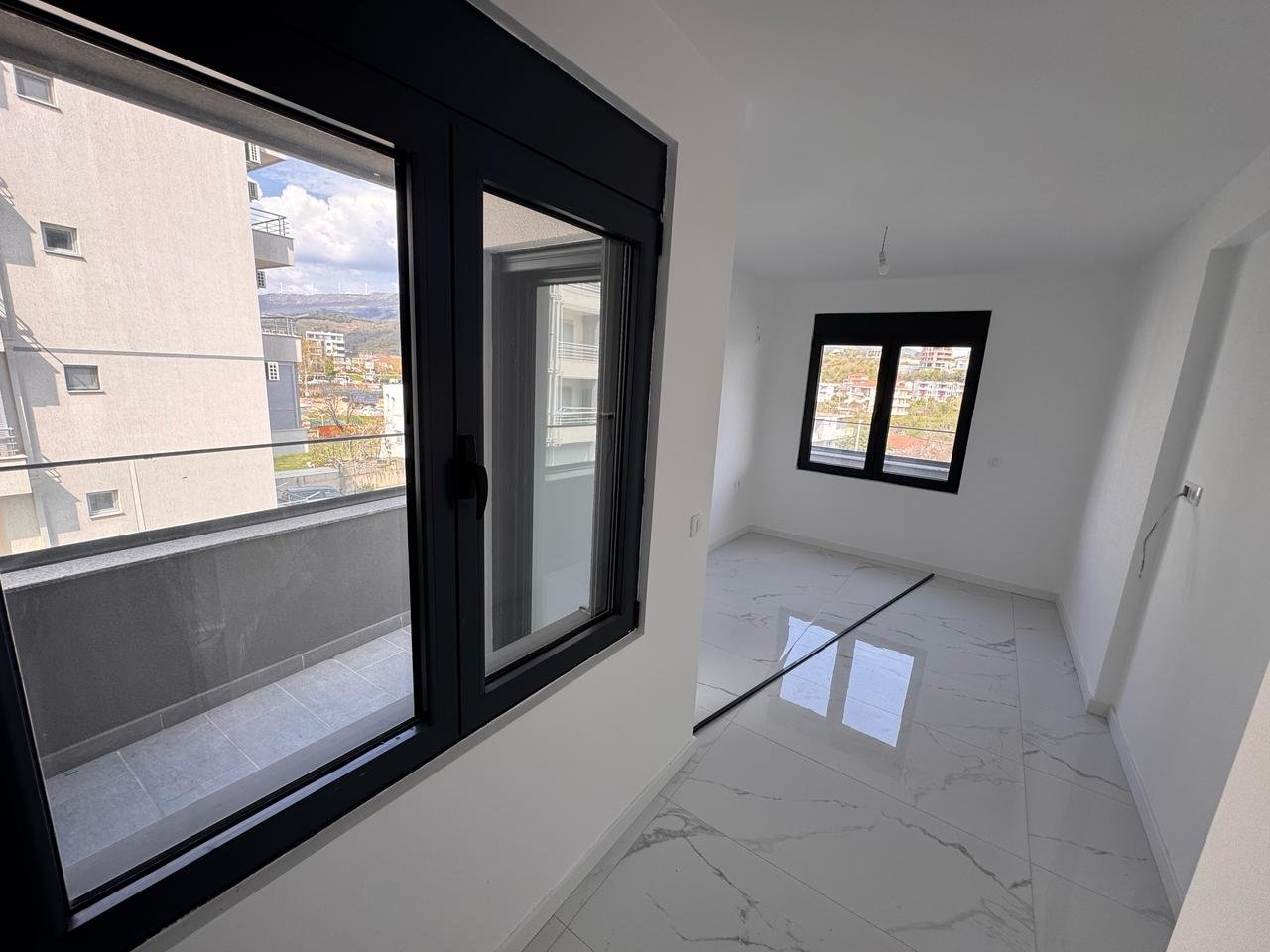 Spacious, sunlit room with white walls, marble floors, balcony views&mdash;prime Ulcinj real estate from immorenta.me by Ekosphere.