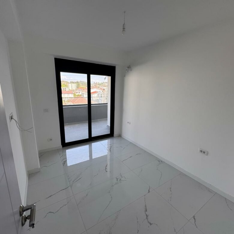 Bright, tiled room in prime Ulcinj real estate; large glass doors to balcony with city views. Exclusive on immorenta.me by Ekosphere doo.