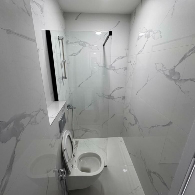 Modern bathroom in Ulcinj with marble tiles, wall-mounted toilet, glass partition&mdash;ideal investment at immorenta.me by ekosphere doo.