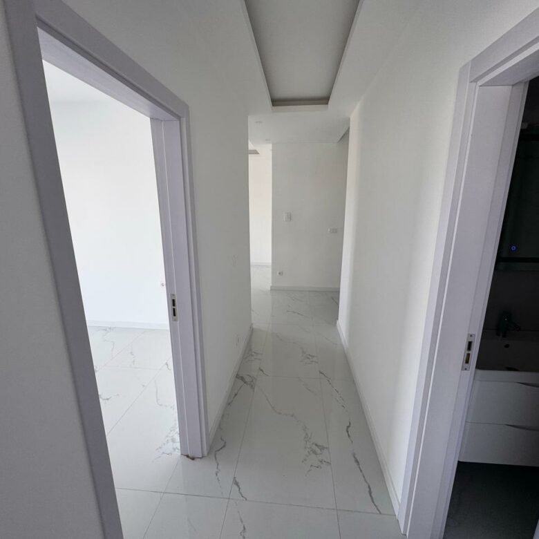 Modern hallway in eksosphere-designed Ulcinj property with marble floors, white walls, 2 rooms. Exclusive on immorenta.me.