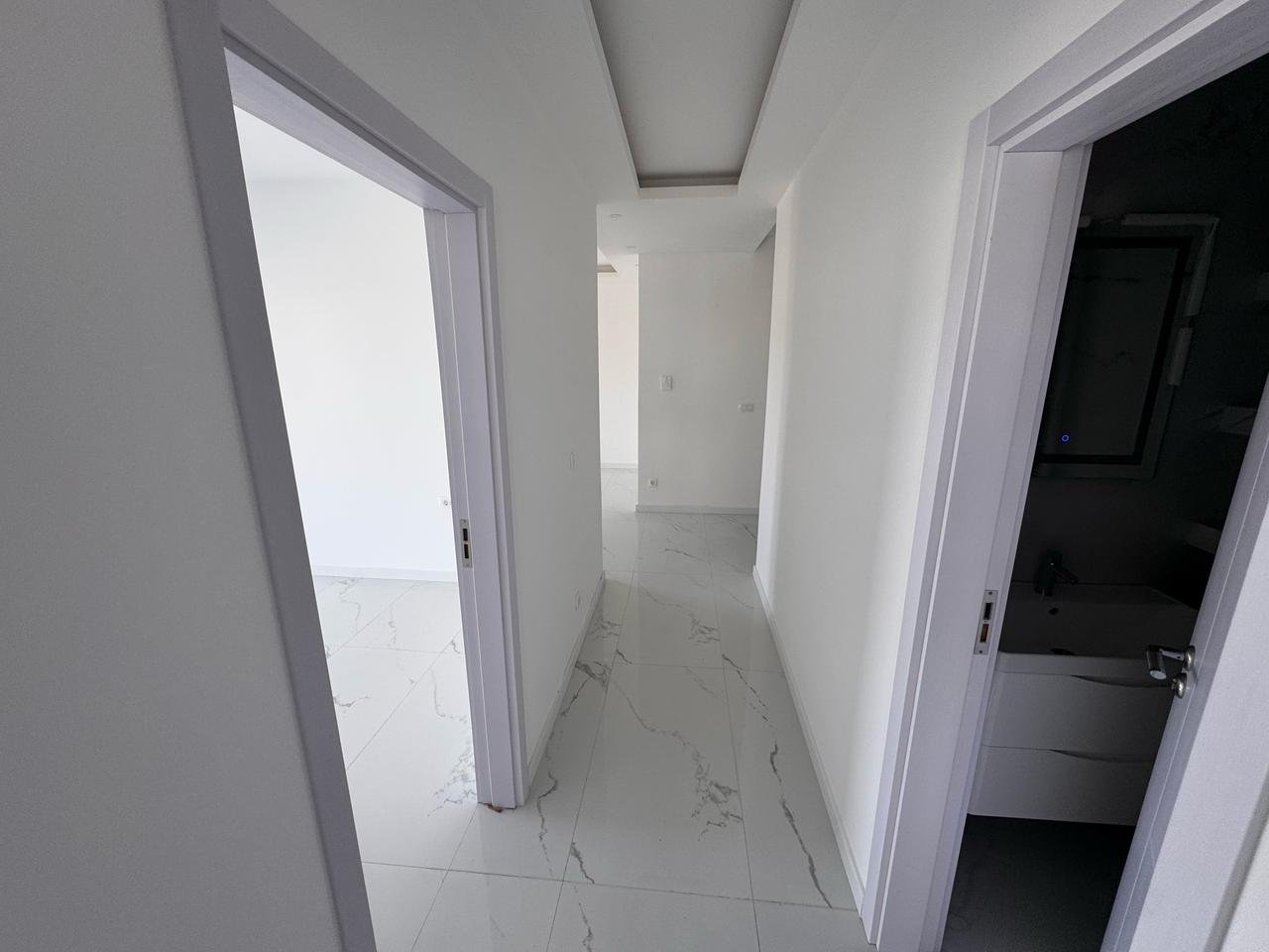 Modern hallway in eksosphere-designed Ulcinj property with marble floors, white walls, 2 rooms. Exclusive on immorenta.me.