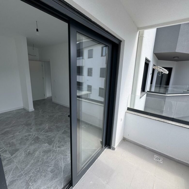 Modern covered balcony with light gray tiles; sliding doors open to airy, unfurnished interiors&mdash;prime Ulcinj real estate at immorenta.me by ekosphere doo.