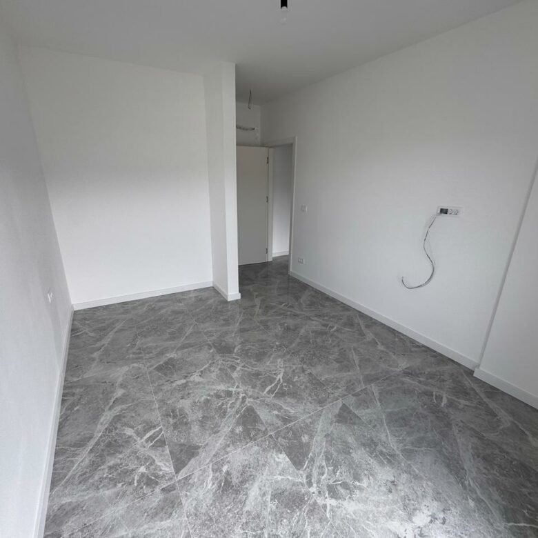 Spacious empty room in Ulcinj, Montenegro with white walls and gray tiled floor&mdash;prime investment from immorenta.me by Ekosphere.