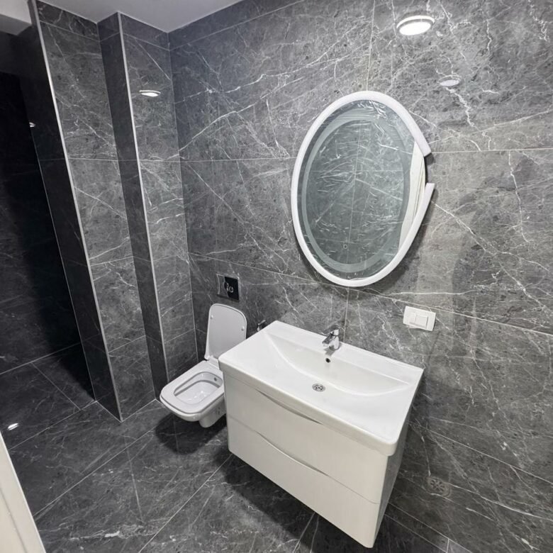 Luxurious modern bathroom with dark marble, wall-mounted toilet, elegant vanity and mirror in Ulcinj&mdash;featured on immorenta.me.
