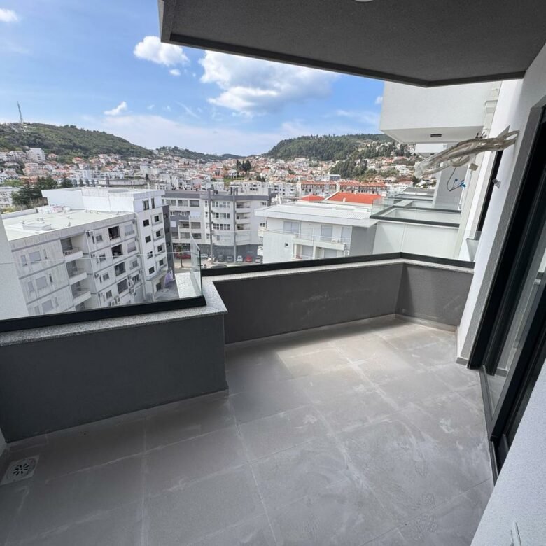 Luxury modern apartment balcony with tiled floors and glass railing, offering stunning Ulcinj city views&mdash;exclusive at immorenta.me by Ekosphere doo.