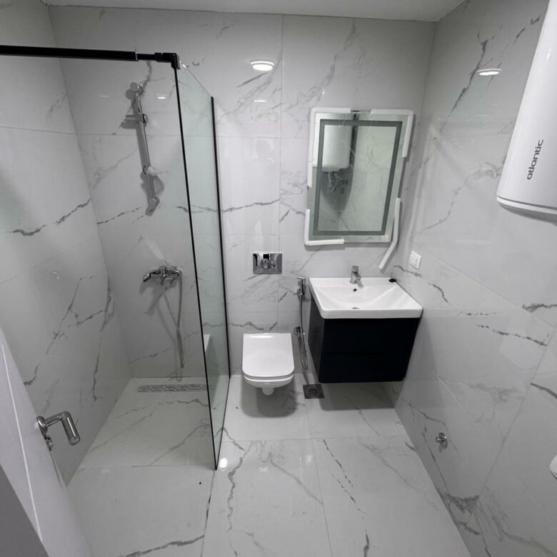 Sleek Ulcinj bathroom with gray marble, wall-mounted toilet, floating sink, glass shower&mdash;exclusive at immorenta.me by Ekosphere.