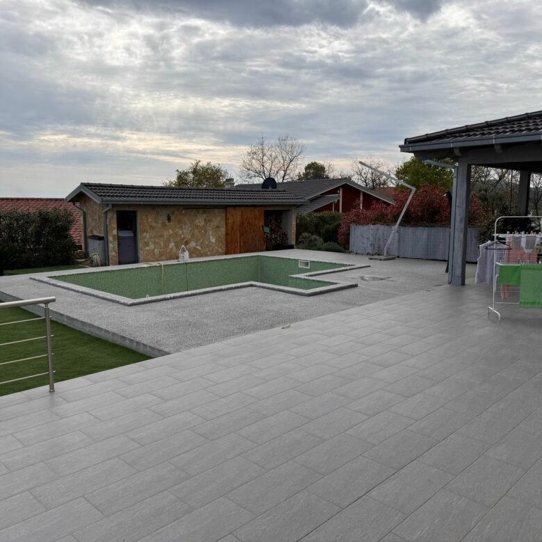 Spacious patio with gray tiles, empty rectangular pool, shed, green lawn&mdash;premium Ulcinj Montenegro property by ekosphere doo.