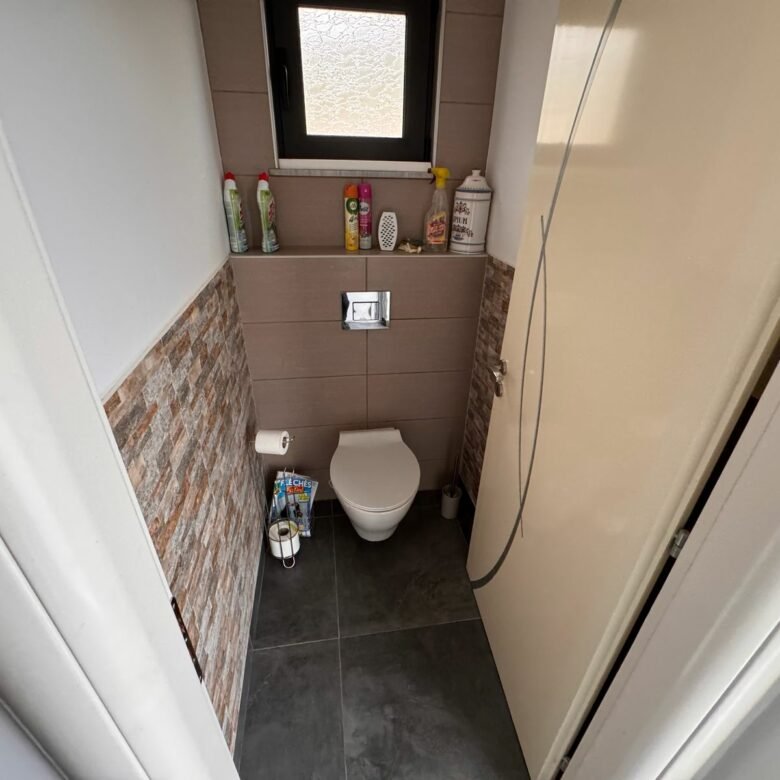 Modern bathroom in Ulcinj property: wall-mounted toilet, bidet, brick/tile accents. Invest with immorenta.me by ekosphere doo.