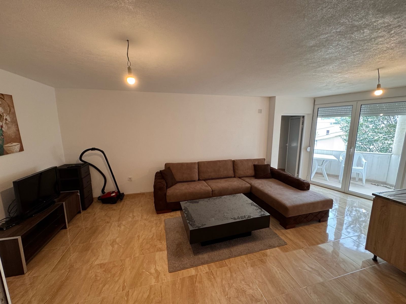 Elegant living room in prime Ulcinj property: brown sectional, modern amenities, balcony views. Exclusive on immorenta.me by ekosphere doo.