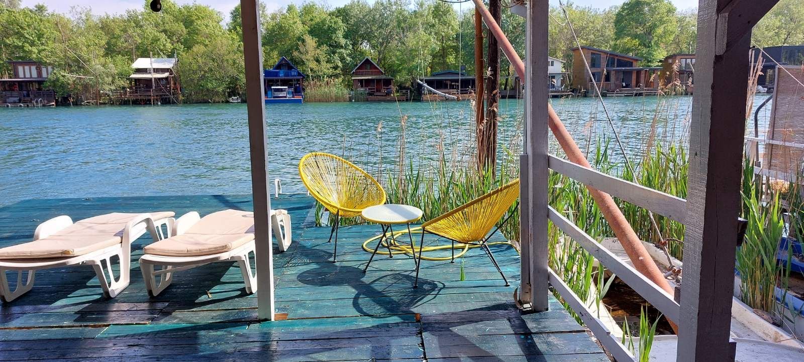 Stunning riverside deck in Ulcinj, Montenegro with yellow chairs and serene river views&mdash;exclusive on immorenta.me by Ekosphere doo.