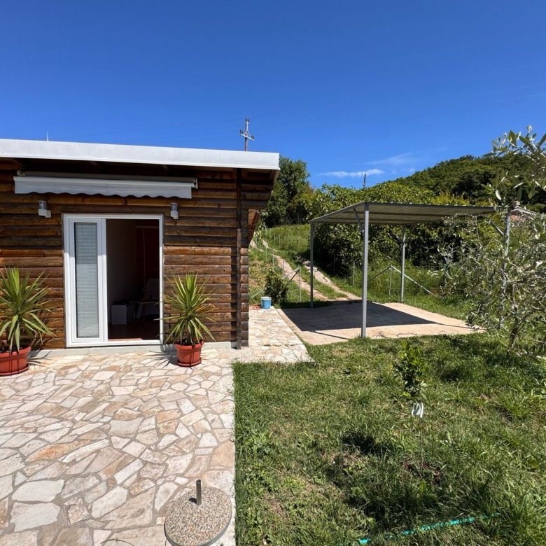 Charming wooden home with stone patio, carport, and lush lawn in Ulcinj. Invest via immorenta.me by ekosphere doo.