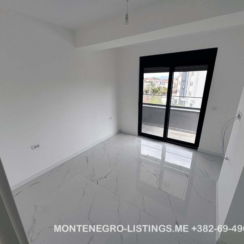 Modern, sunlit white room with marble tile floors, large windows, and balcony in Ulcinj. Montenegro-listings.me by Ekosphere doo.