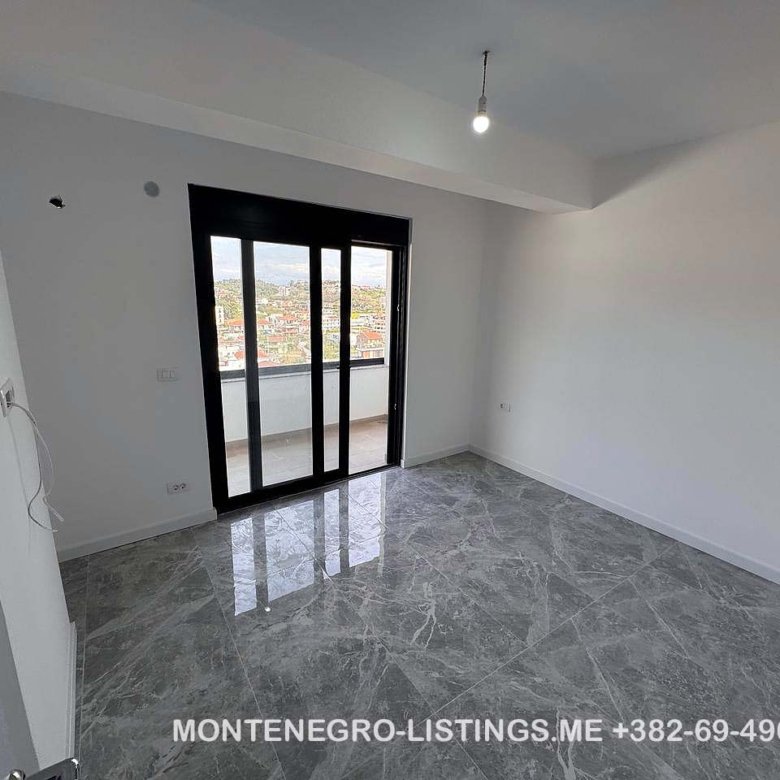 Spacious unfurnished room with tiled floors, balcony access, city and mountain views&mdash;ideal Ulcinj investment on immorenta.me.