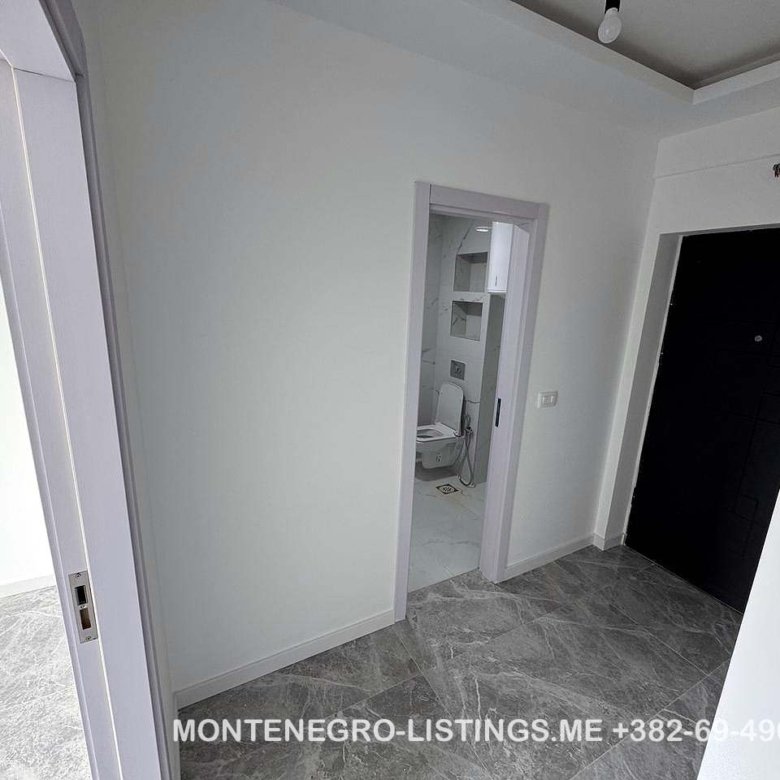 Modern hallway with gray tiled floors, white walls, 3 doors including a bathroom; prime Ulcinj real estate by immorenta.me.