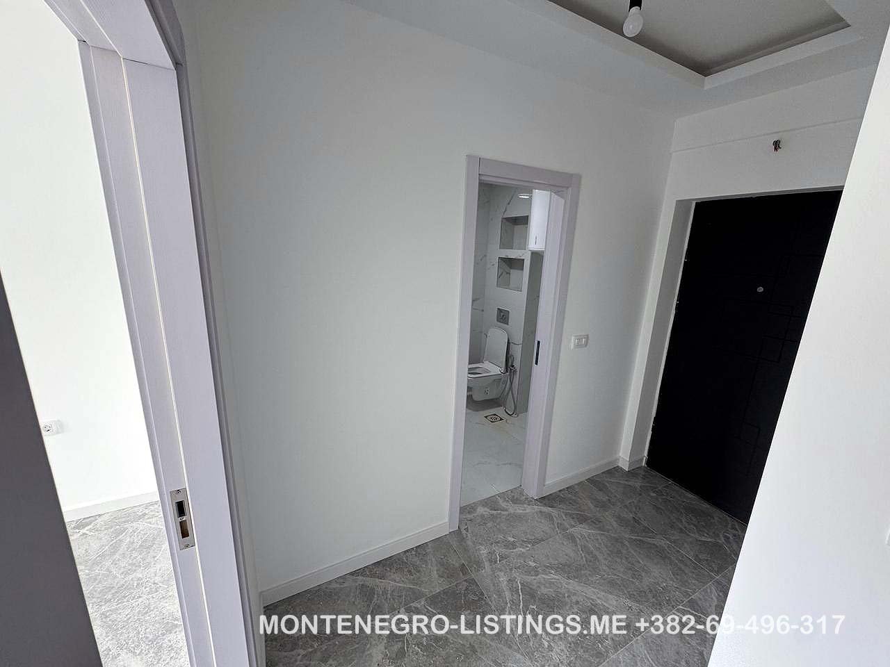 Modern hallway with gray tiled floors, white walls, 3 doors including a bathroom; prime Ulcinj real estate by immorenta.me.