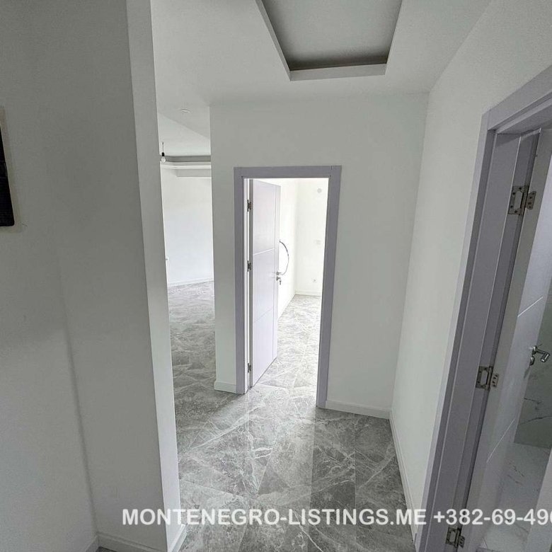 Modern hallway with gray tiles, white walls, and three open doorways in Ulcinj&mdash;exclusive at immorenta.me by ekosphere doo.