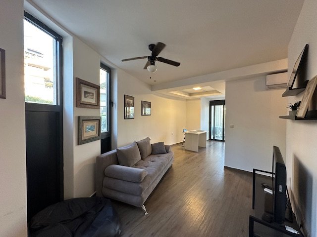 Elegant Ulcinj apartment: gray sofa, TV, wood floors, dining area & views&mdash;prime Montenegro real estate by Ekosphere on immorenta.me.