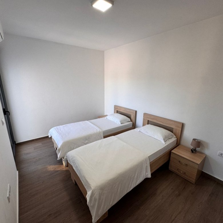 Modern Ulcinj bedroom: two single beds, white bedding, AC, wood floors&mdash;prime Montenegro real estate via immorenta.me/Ekosphere.