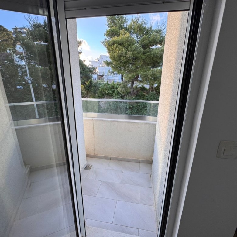 Bright balcony with beige tiles and glass railing in Ulcinj&mdash;ideal property investment. View at immorenta.me by ekosphere doo.