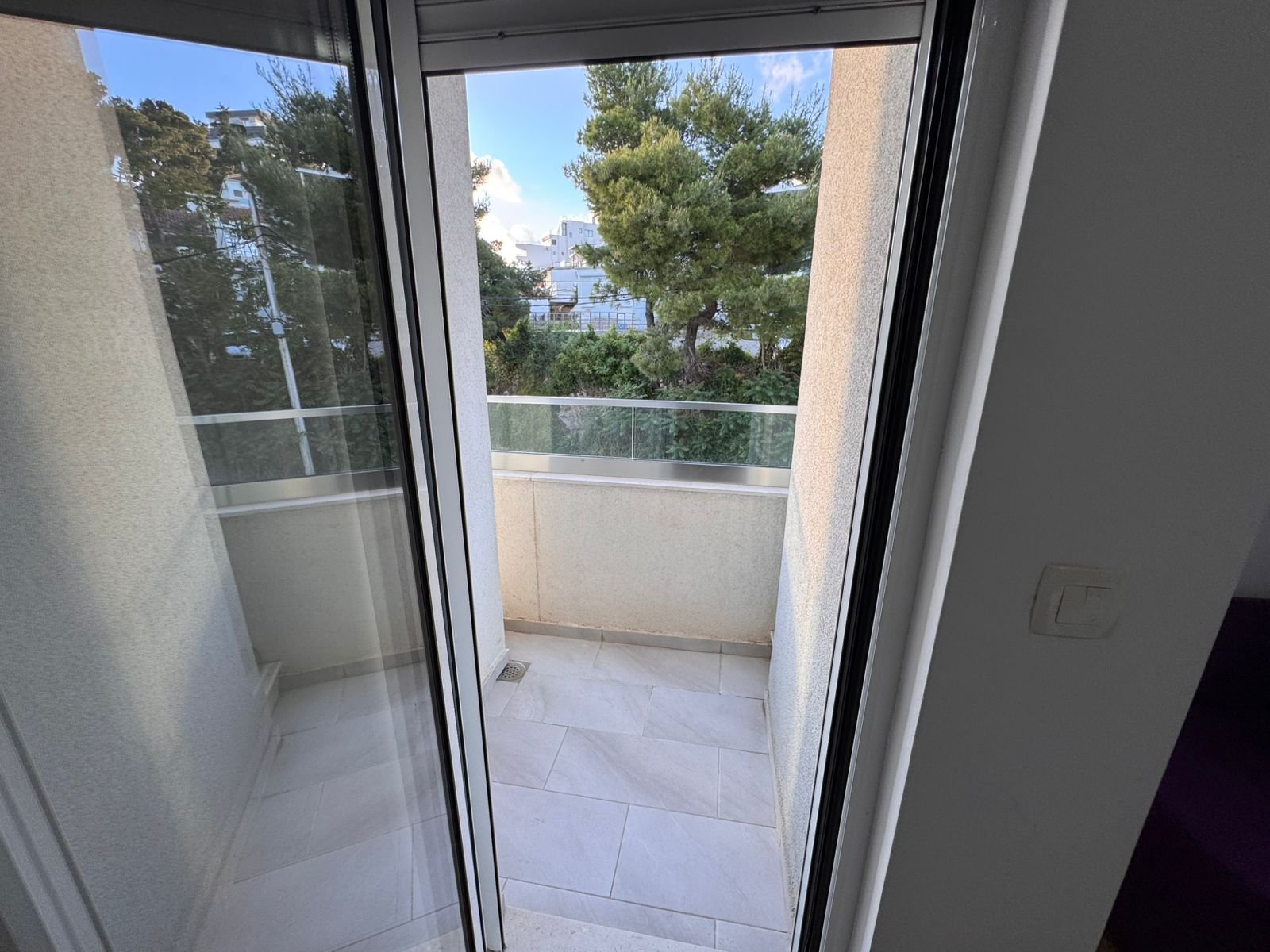Bright balcony with beige tiles and glass railing in Ulcinj&mdash;ideal property investment. View at immorenta.me by ekosphere doo.