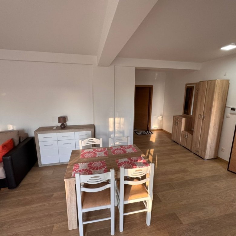 Elegant dining area with wooden table, sideboard, and sofa, ideal Ulcinj investment. Montenegro-listings.me by ekosphere doo.