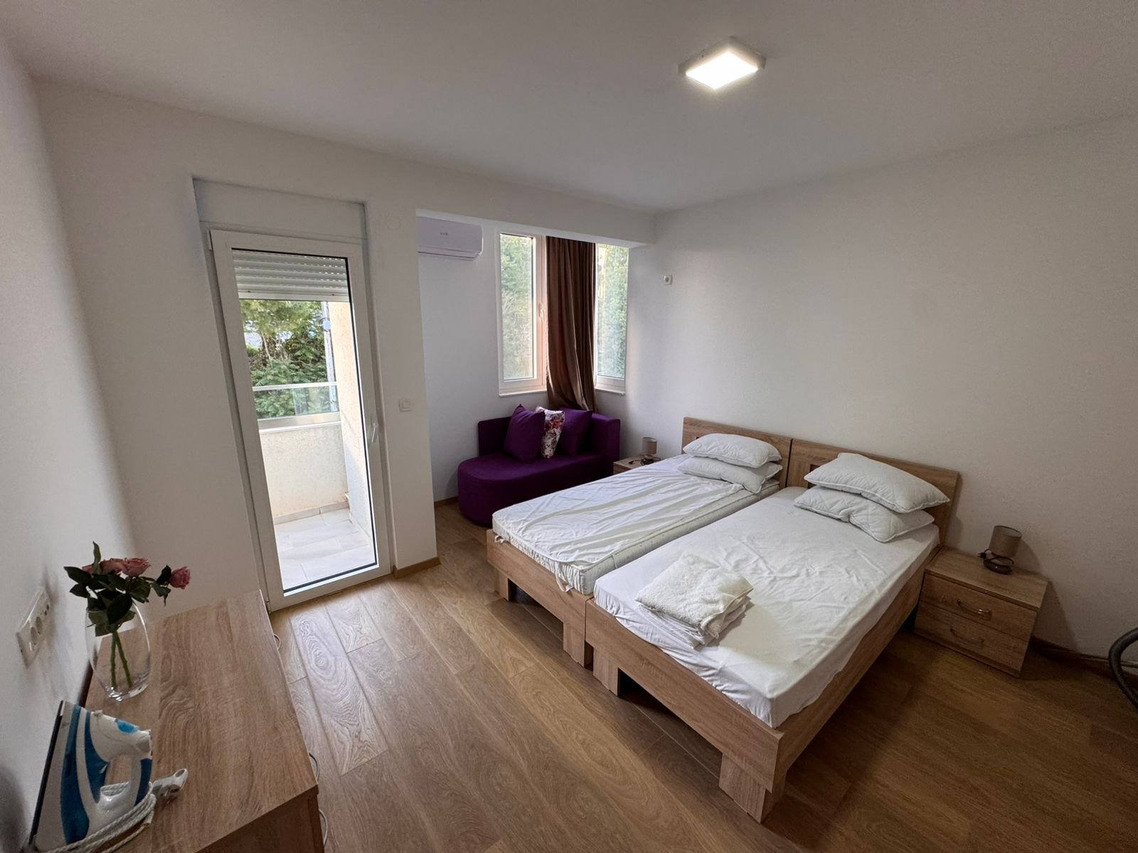 Elegant Ulcinj bedroom with twin beds, purple sofa, balcony & lush views. Prime real estate by Ekosphere on immorenta.me.