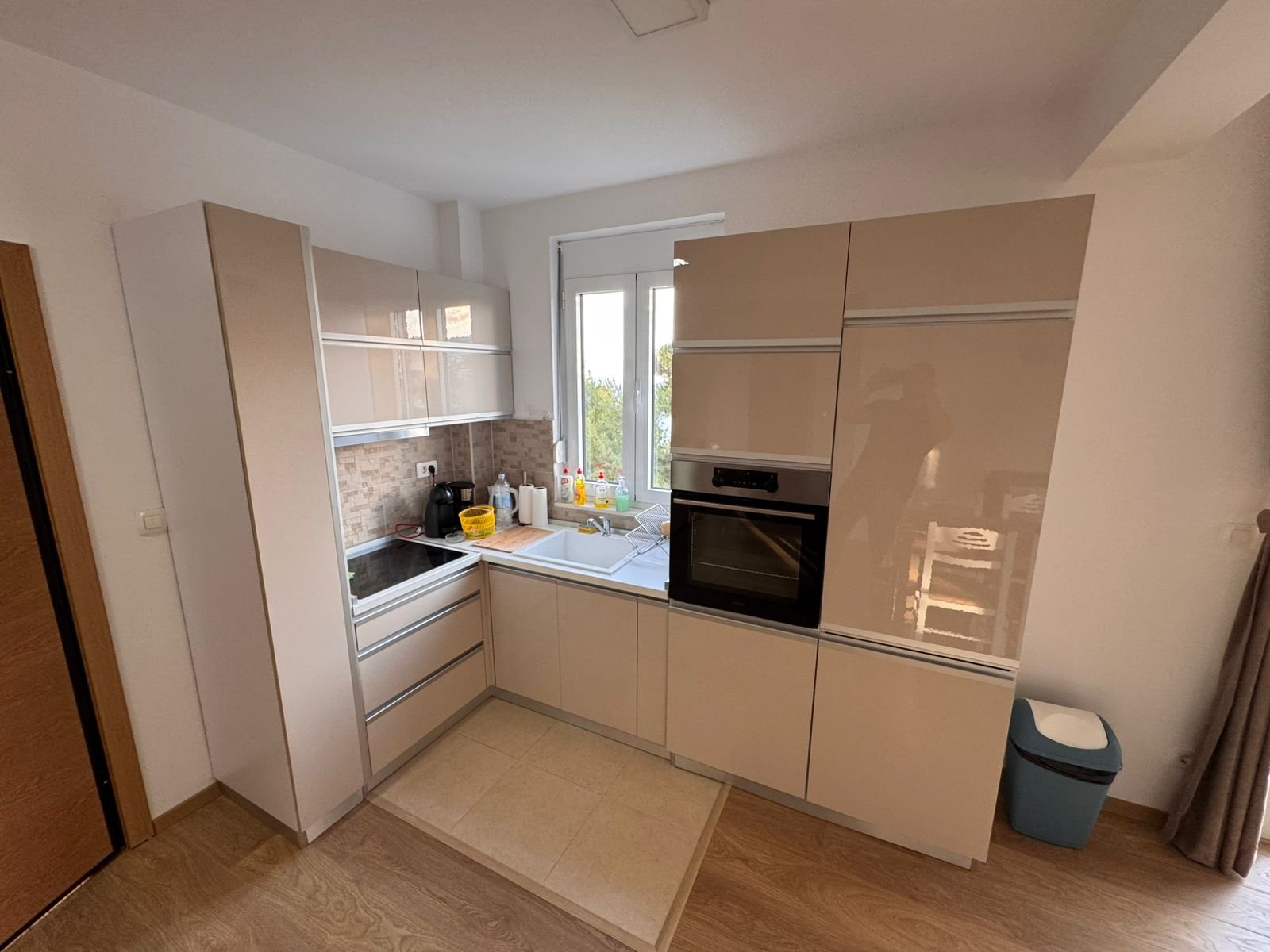 Stylish modern kitchen in Ulcinj with beige cabinets, built-in oven, and wooden flooring&mdash;exclusive on immorenta.me by ekosphere doo.