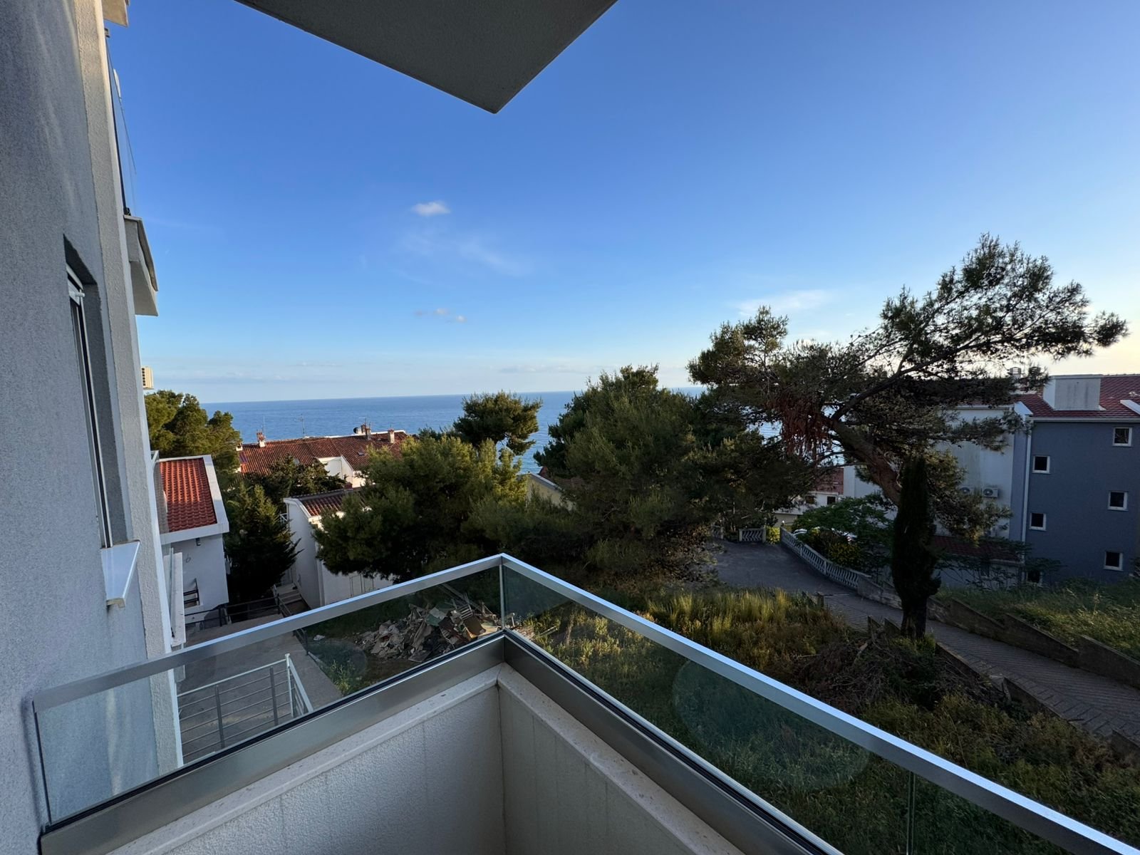 Stunning glass-railed balcony view over sea, rooftops, and greenery&mdash;prime Ulcinj Montenegro property at immorenta.me by Ekosphere doo.