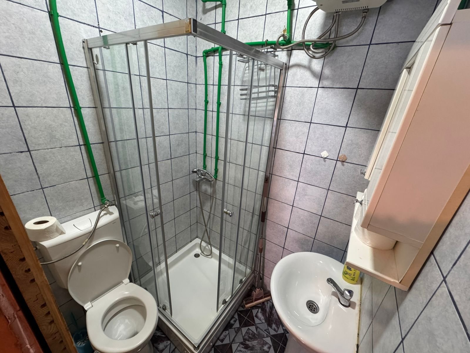 Modern bathroom in Ulcinj property: corner shower, wall sink, blue-accented tiles. Exclusive at immorenta.me by ekosphere doo.