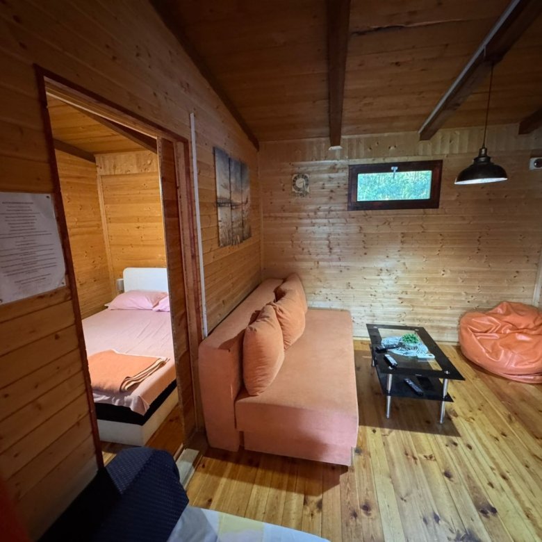 Charming Ulcinj cabin for sale&mdash;wood accents, orange sofa, modern TV, open bedroom. Invest with immorenta.me by ekosphere doo.
