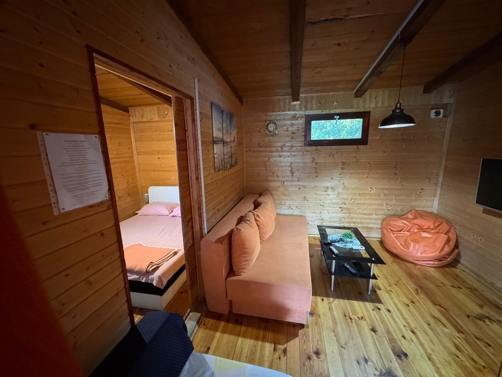 Charming Ulcinj cabin for sale&mdash;wood accents, orange sofa, modern TV, open bedroom. Invest with immorenta.me by ekosphere doo.