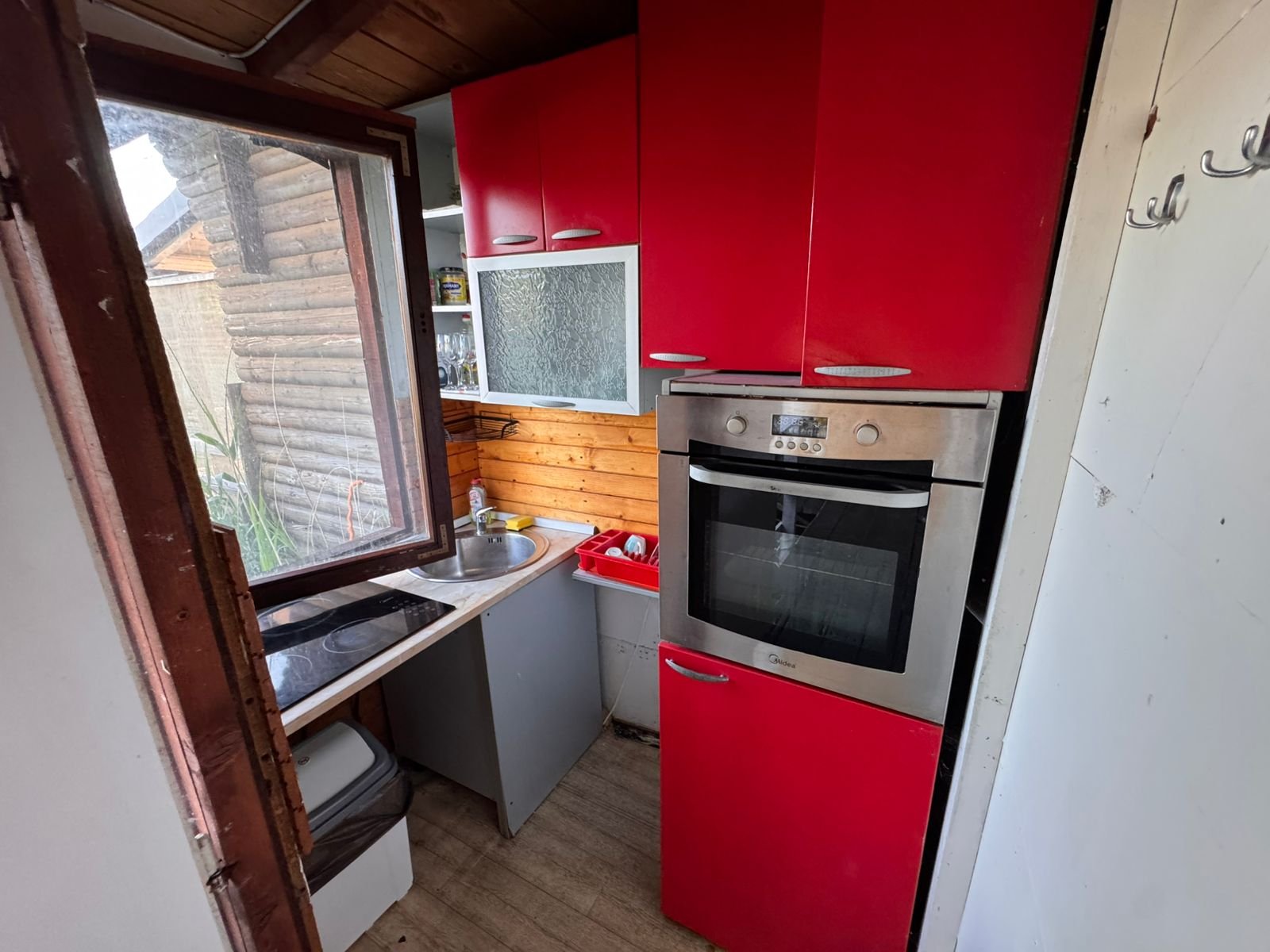 Chic Ulcinj kitchen: red cabinets, stainless oven, wood accents. Bright and inviting. Exclusive on immorenta.me by Ekosphere doo.