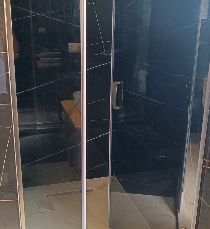 Luxurious shower with marble-patterned tiles, glass panels, and wood accents&mdash;exclusive property in Ulcinj by ekosphere doo on immorenta.me.