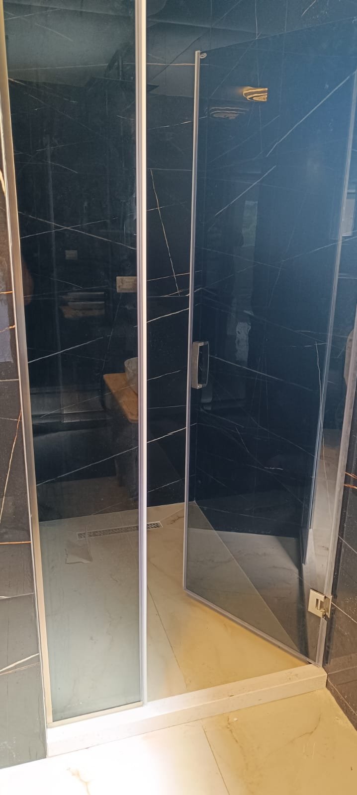 Luxurious shower with marble-patterned tiles, glass panels, and wood accents&mdash;exclusive property in Ulcinj by ekosphere doo on immorenta.me.