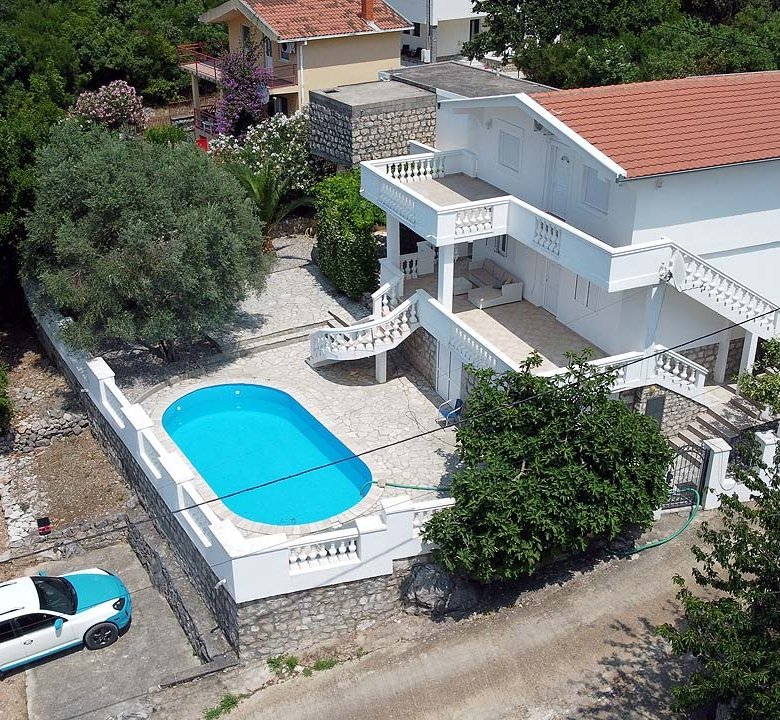 Stunning Ulcinj villa: white two-story home, red roof, pool, balcony, lush grounds. Prime investment at immorenta.me by Ekosphere.