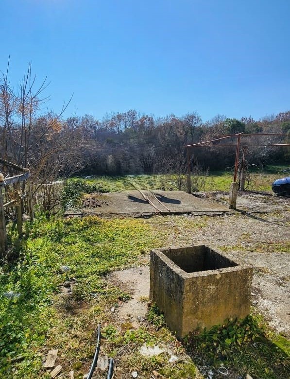 Prime Ulcinj property: spacious sunlit yard with concrete well, lush greenery&mdash;ideal for investment. Listed by immorenta.me, an ekosphere doo project.
