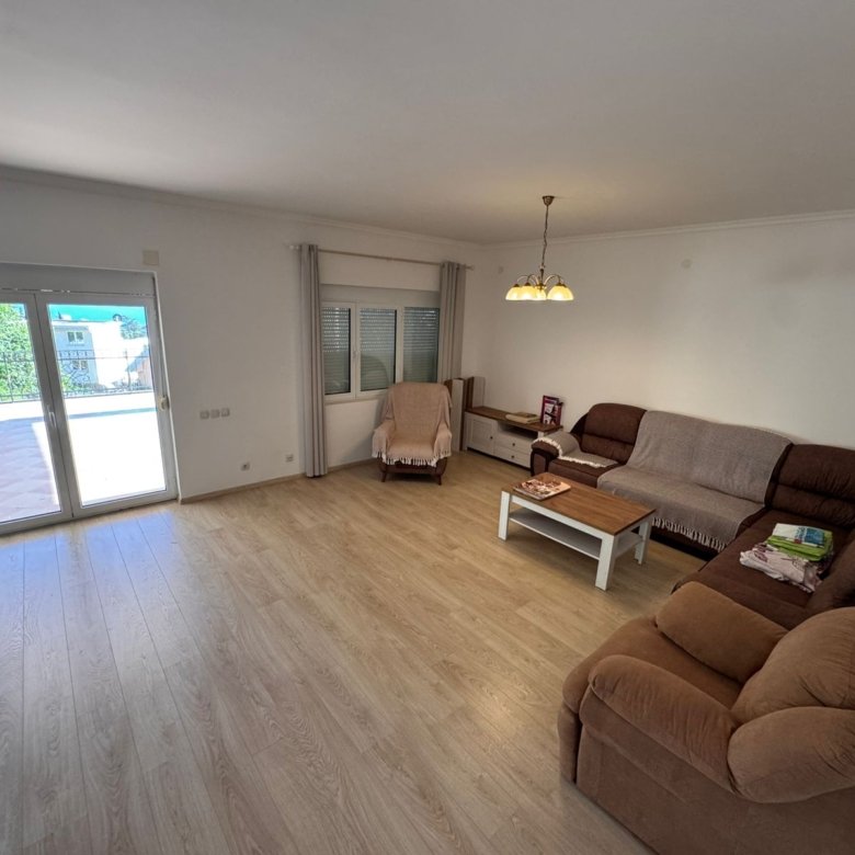 Elegant Ulcinj apartment: light wood floors, brown sectional, balcony access. Invest via immorenta.me by ekosphere doo.