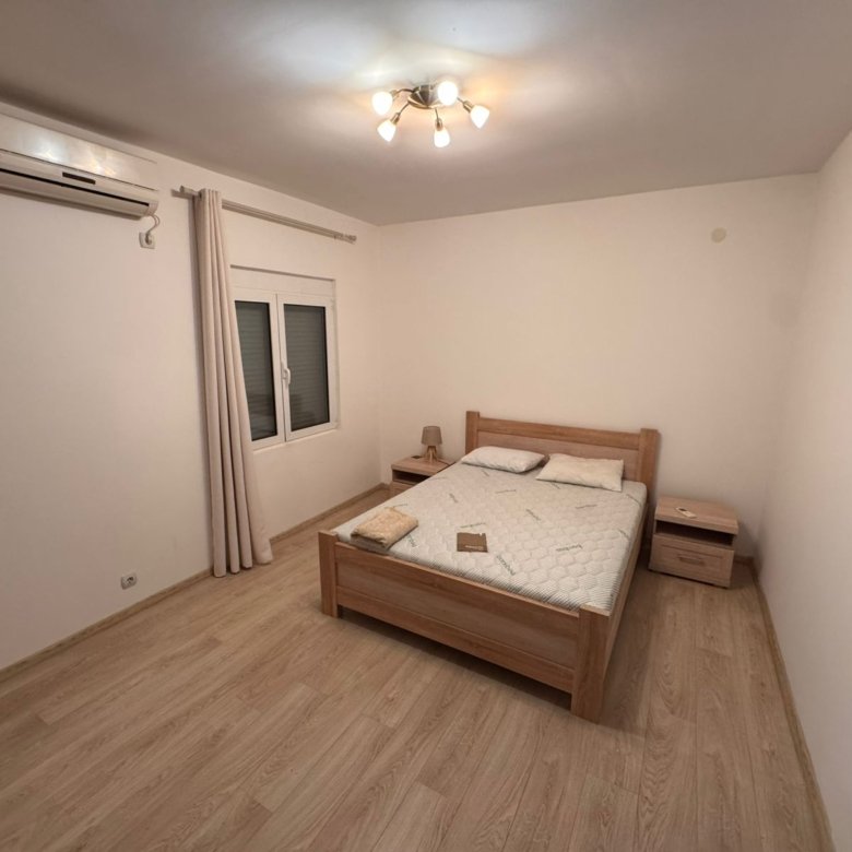 Modern Ulcinj bedroom with light wood floors, double bed, AC, and elegant finishes&mdash;prime Montenegro real estate by Ekosphere doo.
