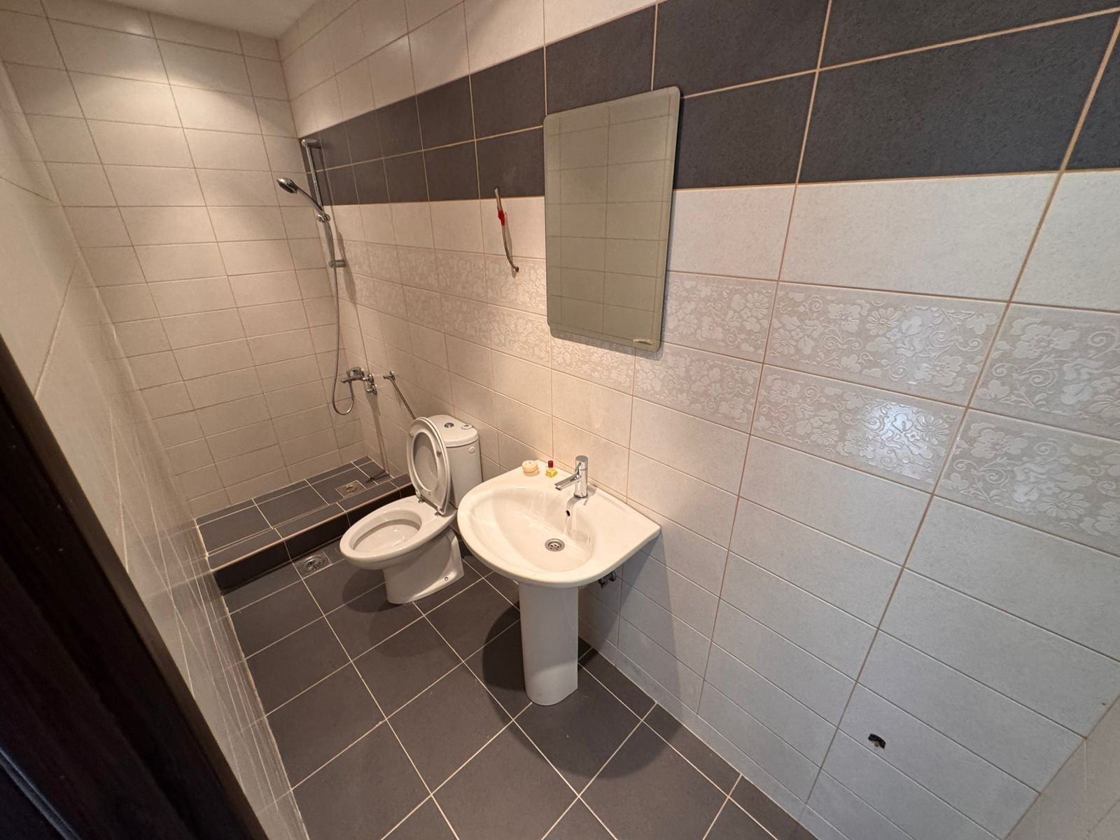 Modern Ulcinj Montenegro property bathroom: tiled in gray and white, with shower, sink, and mirror. Discover more on immorenta.me by ekosphere doo.